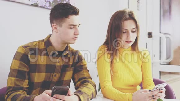 可爱的女孩坐在咖啡馆的桌子旁他在看他女朋友手机快关门复制空间视频的预览图