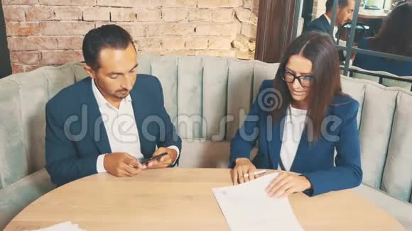 两个商人在一家咖啡馆工作他们正在讨论和准备合同老板正在签署文件顶部视图视频的预览图