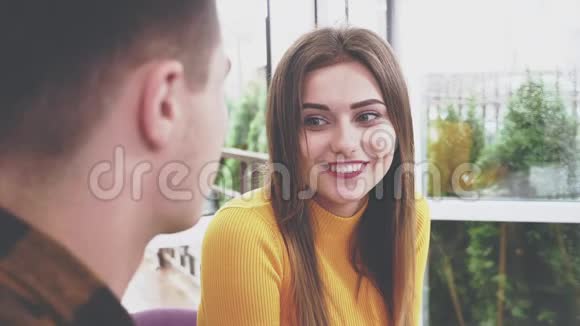 可爱的女孩坐在咖啡馆的桌子旁她正在和她的男朋友说话他握着她的手真诚的微笑视频的预览图