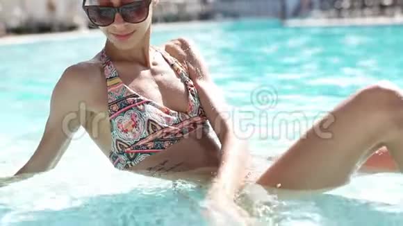 美丽的女孩戴着黑色太阳镜拥有惊人的超级苗条身材在游泳池放松享受温暖的夏日视频的预览图