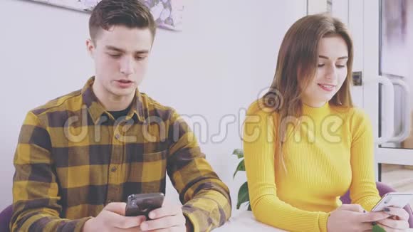 可爱的一对夫妇坐在咖啡馆的桌子旁他们正在手机上输入新的信息快关门复制空间视频的预览图