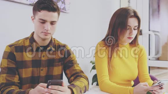 可爱的女孩坐在咖啡馆的桌子旁他们在手机上互相展示一些东西快关门副本视频的预览图