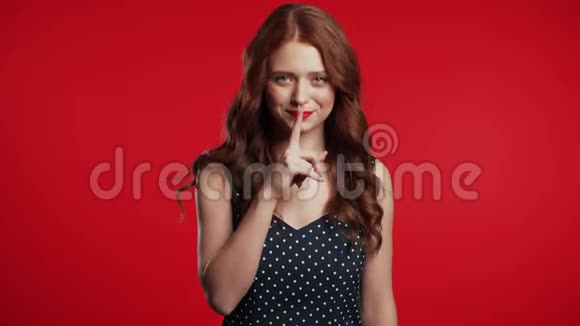 积极的女孩拿着手指在她的嘴唇上的红色背景什赫的姿态视频的预览图