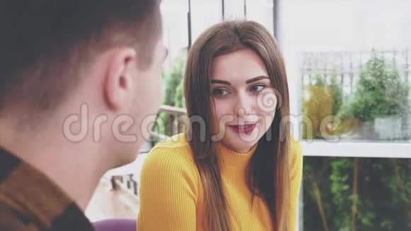 可爱的女孩坐在咖啡馆的桌子旁她正在和她的男朋友交流男朋友牵着她的手真诚真诚视频的预览图