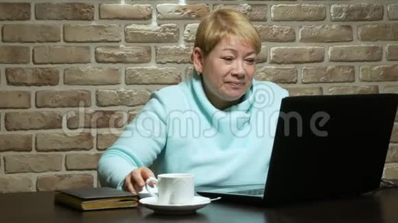 一位老年妇女用笔记本电脑在电视会议上讲话视频的预览图