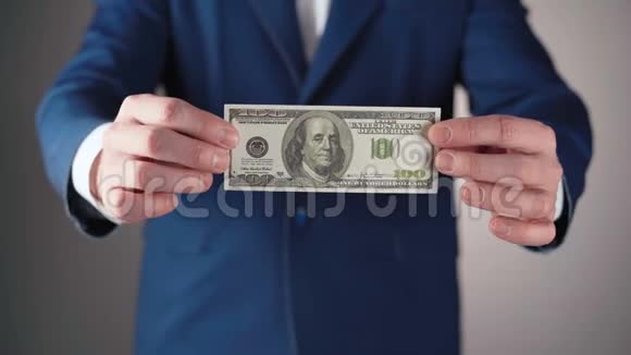 穿着蓝色夹克的商人手里拿着美元的照片视频的预览图