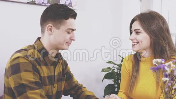 可爱的女孩坐在咖啡馆的桌子旁她正在和她的男朋友交流他正在亲吻她的手视频的预览图
