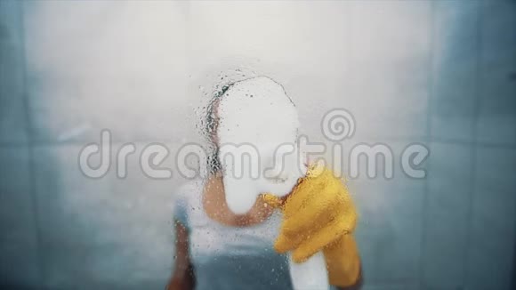 那个女人在浴室里洗了一扇窗户把肥皂水溅在玻璃上把玻璃从污垢中清除快关门4K视频的预览图