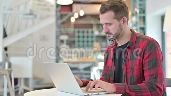 在咖啡厅镜头前拿着手提电脑微笑的年轻人视频的预览图