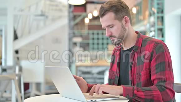 有笔记本电脑的年轻人在咖啡厅里讲智能手机视频的预览图