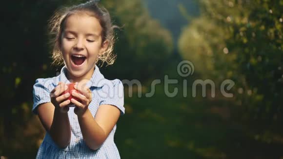 饥饿的女孩在户外咬一个红苹果女孩笑容满面快关门复制空间4K视频的预览图