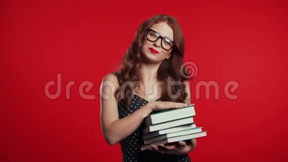 画室里红色背景的欧洲学生持有一堆大学书籍视频的预览图
