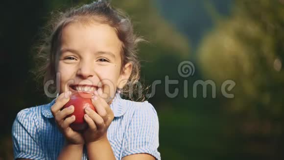 小女孩正拿着一个红苹果靠近她的脸女孩笑容满面快关门复制空间4K视频的预览图