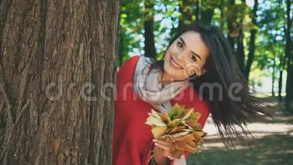 快乐微笑的白种人女孩正带着一束秋叶从树上露出来与世隔绝在模糊的公园里视频的预览图