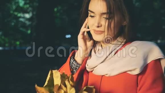 可爱的女孩在打电话抱着一束秋叶背景模糊作物快关门复制空间4K视频的预览图