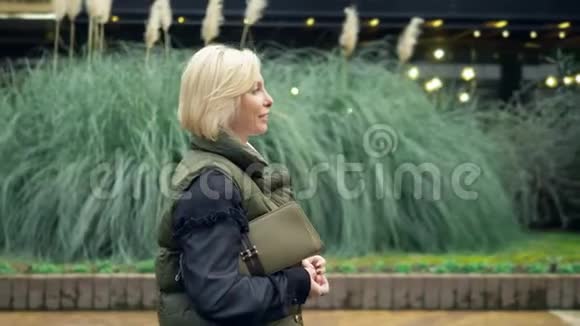 秋天美丽时尚的金发女郎在城市公园散步视频的预览图