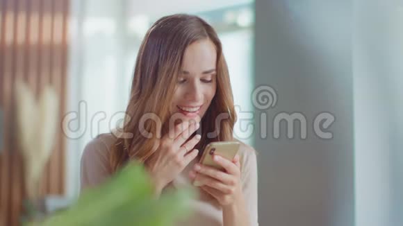 女性在家里的智能手机上阅读信息厨房用手机的女孩视频的预览图