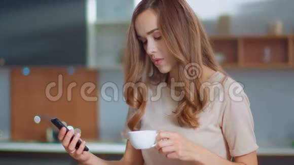 女人在家里的智能手机上自拍照片女孩在厨房喝咖啡视频的预览图