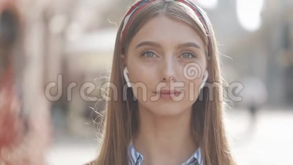一位年轻美丽的女士戴着无线耳机对着镜头微笑站在老人身上的画像视频的预览图
