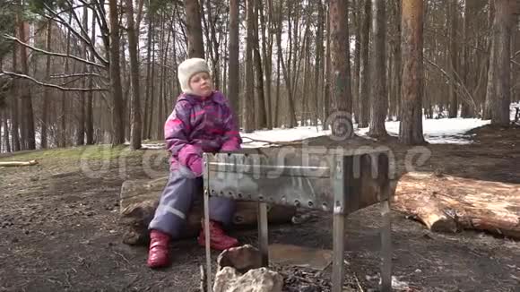 坐在松林边缘烤架附近的女孩视频的预览图