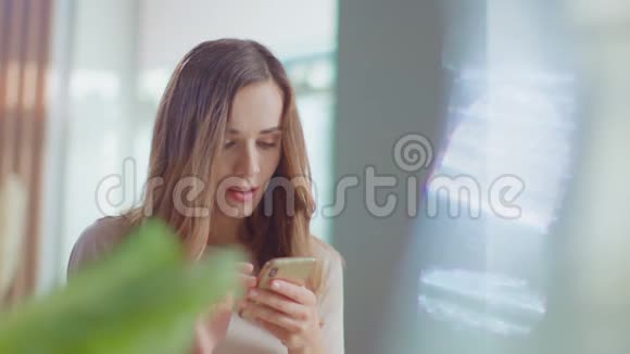 女人在家里的智能手机上收到好消息在室内使用手机的女孩视频的预览图