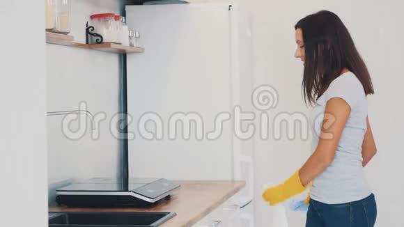 戴着黄色橡胶手套的女人正在厨房用除脂剂喷雾剂和除尘器清洗烹饪面板快关门4K视频的预览图