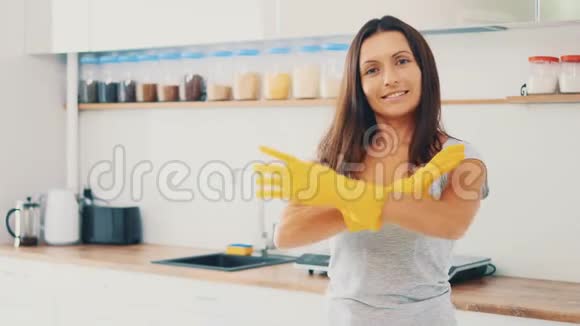 家务活漂亮的女人戴着黄色的橡胶手套真诚地微笑着在厨房的背景下副本视频的预览图