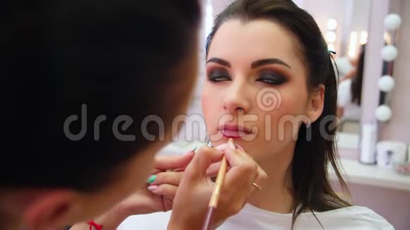 化妆师描绘了年轻女孩的嘴唇用铅笔圈出唇边化妆师为你化妆视频的预览图