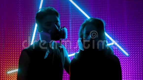 在俱乐部霓虹灯下的年轻夫妇dubstep或朋克风格的概念戴着来自肮脏空气的防毒面具视频的预览图