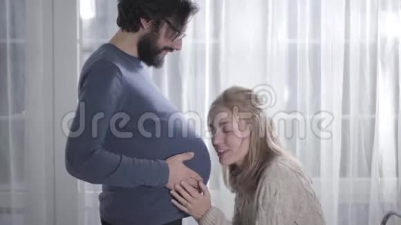 嘲笑白人女孩把耳朵贴在丈夫怀孕肚子上积极的女人听宝宝心跳有趣搞笑视频的预览图