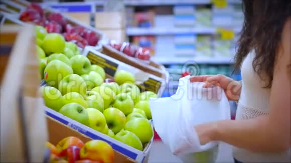 女人在超市里买食物水果苹果桔子女孩在超市里挑选食物蔬菜水果视频的预览图