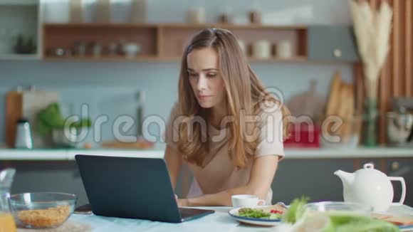 女商人在家里办公室用笔记本电脑在厨房工作的女人视频的预览图