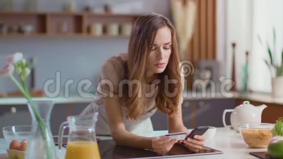 在厨房拿智能手机的女人女士早上在家喝咖啡视频的预览图