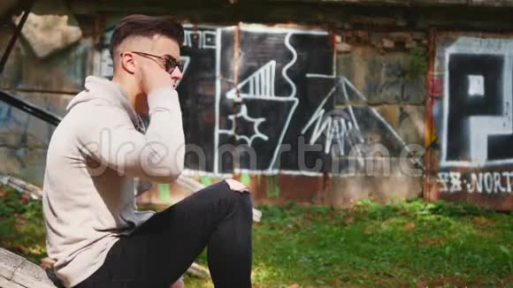 自信和放松的家伙穿着休闲服他坐在外面听着带着耳机的音乐视频的预览图