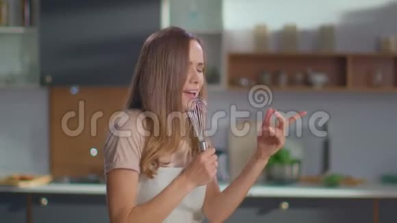 快乐的女人在厨房跳舞家庭主妇在厨房边唱边唱视频的预览图