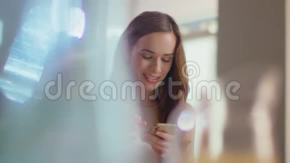 微笑的女人在家里使用智能手机女士持手机室内视频的预览图