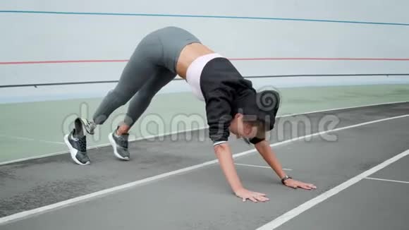 残疾妇女在体育场伸腿女孩在运动跑道上练习瑜伽视频的预览图