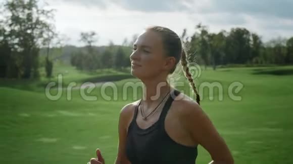 快乐的女运动员在绿色的田野里慢跑在公园跑步的女人视频的预览图