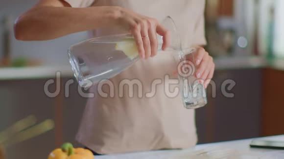 女人从水壶里往玻璃杯里倒水女士在家喝水视频的预览图