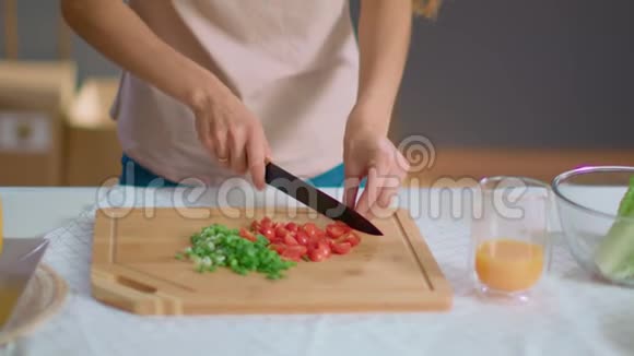 家庭主妇在厨房的木板上切菜女士吃番茄视频的预览图