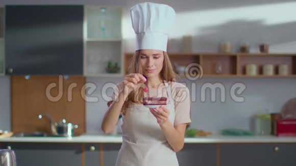 糖果师在工作场所用樱桃装饰蛋糕女人看着摄像机视频的预览图