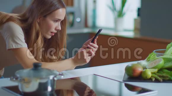 女人在厨房用智能手机拍照食物使用手机的博客视频的预览图