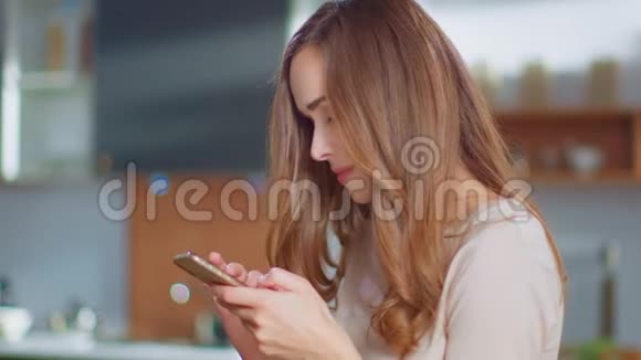 女人在家里在智能手机上聊天厨房用手机的女孩视频的预览图