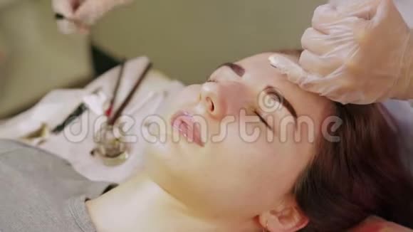 美容师从顾客的眉毛上清洗指甲花并涂上一种特殊的奶油视频的预览图