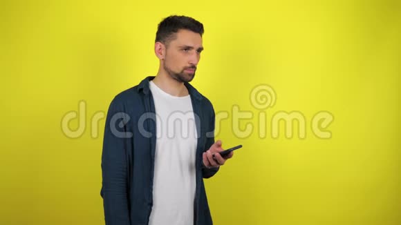 一个穿着蓝色衬衫和白色T恤的年轻人在智能手机上打电话看着相机微笑视频的预览图