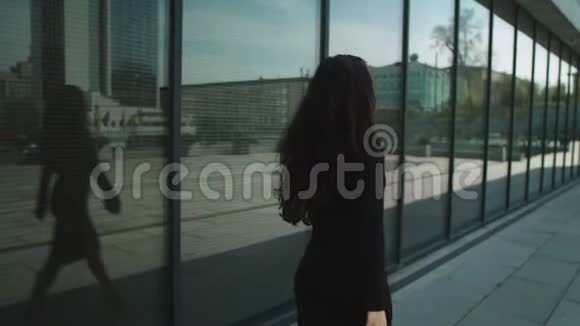 后视女企业家摸头发穿着裙子走在街上的女人视频的预览图