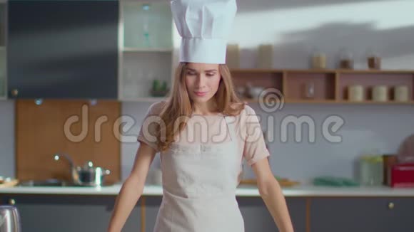微笑的厨师站在厨房里女厨师戴着帽子双手交叉着厨房视频的预览图
