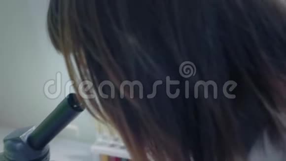 年轻的女科学家透过显微镜看她研究样本一位年轻的科学家进行科学研究视频的预览图