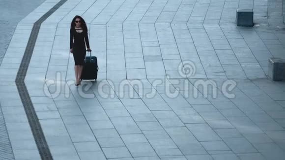 带着行李在街上走的女人女人带着手提箱向外看视频的预览图