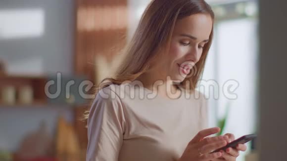 女人在厨房的智能手机上发短信女士在家里用手机视频的预览图
